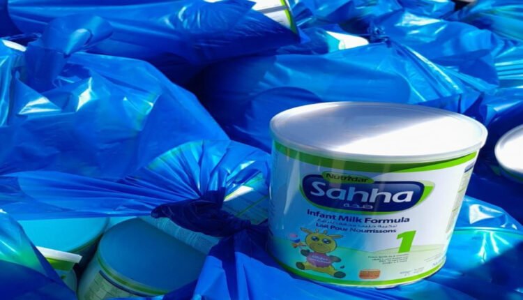 Infant milk formula can among blue garbage bags, highlighting packaging waste.